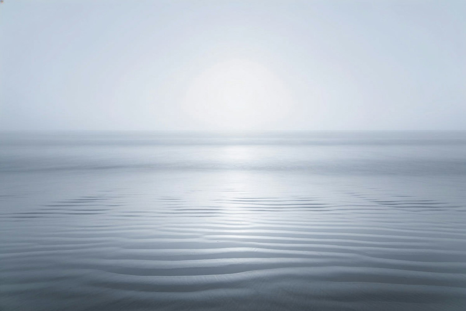 Long exposure of a calm sea under an overcast sky, horizon almost dissolved